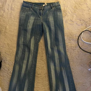 Blå bootcut jeans med randigt mönster - Unika blå jeans med bootcut passform och vertikalt randigt mönster. Tillverkade i stretchig denim med 96% bomull och 4% elastan för extra komfort. Klassisk femficksmodell och snygga kontrastsömmar. Perfekta för dig som vill sticka ut.