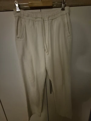 Beiga mjukisbyxor från Zara M - Säljer ett par beiga mjukisbyxor från Zara i storlek M. Byxorna har resårmidja med snörning, sidofickor fram och bakfickor. Tillverkade i mjukt bomullsmaterial för en chill och avslappnad look.