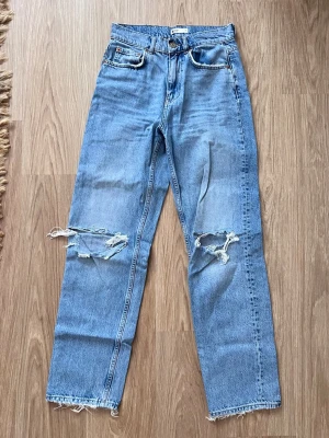Ljusblå raka jeans med slitna knän från Gina Tricot, storlek 36 - Ljusblå jeans med rak passform och slitna detaljer över knäna och fransiga benslut. Sälja pga att de inte används längre. Bra kvalitet! - Köper du innan kl 16:00 kan jag posta samma dag!
