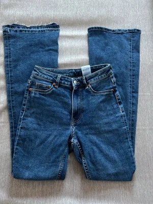 Blå bootcut jeans - Klassiska blå Levi's 501 jeans med rak passform och fem fickor. Jeansen har hög midja och rå, uppsprettad kant längst ner på benen som är lätt att sy upp till sin ursprungliga design. Tillverkade i slitstarkt denim med metallknappar och nitar.