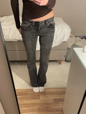 Mörkgrå lågmidjade bootcut jeans - Mörkgrå lågmidjade Bootcut jeans från Gina.  Innerbenslängd: 78cm                                   Midjemåttet: 35,5cm                                    Grenhöjd: 19cm