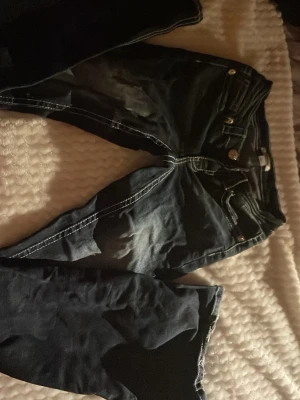 Svarta jeans med broderade bakfickor XS - Säljer ett par svarta jeans från Gina Tricot i storlek XS. Jeansen har snygga broderade detaljer på bakfickorna och kontrasterande vita sömmar. Byxornas kant vid hälarna har båda slitits. Perfekta jeans för dig som gillar unika detaljer.