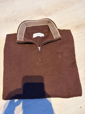 Mr capuchin half zip - Säljer en brun stickad tröja från Mr. Capuchin i storlek small. Tröjan har en snygg half zip-dragkedja och krage med beige detalj. Perfekt för lager på lager under höst och vinter. Enkel och stilren design som funkar till det mesta. 