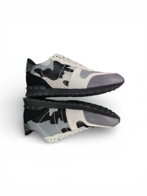 Valentino Rockrunner sneakers camo - Snygga Valentino Rockrunner sneakers med grå, svart och vit camouflage. Skorna har detaljer i mocka och skinn, samt coola nitar på sulan. Klassisk snörning och rund tå. Perfekta för dig som vill sticka ut med en lyxig streetstyle.