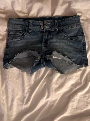 Blå jeansshorts från Nelly - Säljer ett par lågmidjade blåa jeansshorts från Nelly i stl 36, skit snygga och korta till sommarn.