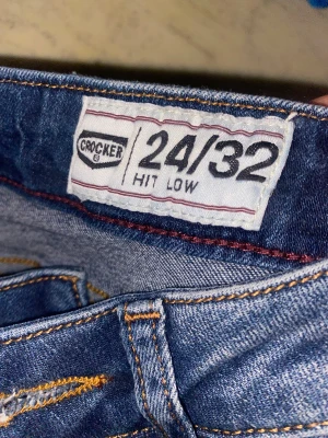 Blå Crocker skinny jeans låg midja - Säljer ett par blå skinny jeans från Crocker i storlek 24/32. Modellen har låg midja och klassisk femficksdesign med snygga kontrastsömmar. Jeansen är tillverkade i jeansmaterial och har en smal passform.