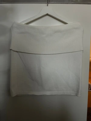 Vit stickad kjol med ribbad kant - Snygg vit stickad kjol med bred ribbad kant upptill och nedtill. Kjolen har en enkel, rak form och är perfekt för dig som gillar en clean och stilren look. Mjuk och skön stickad kvalitet som känns cozy och trendig.