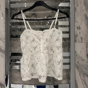 Vitt Hollister linne - Säljer ett vitt Hollister linne i storlek XS. Den är i spets material, har justerbara band och knappar på framsidan. 