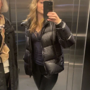 Svart dunjacka  med dragkedja - Säljer en svart pufferjacka med hög krage och dragkedja framtill. Jackan är vadderad och har en oversized passform.