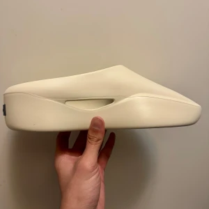 Fear of God Eva Runner strl 42 - Minimalistiska sneakers/slippers från Fear of God Eva runner i crème färg. Helt nya. Köpt från Farfetch.com så köpbevis finns.  Made in Italy Levereras med originalbox och dustbags. Perfekta för dig som gillar clean och modern stil.