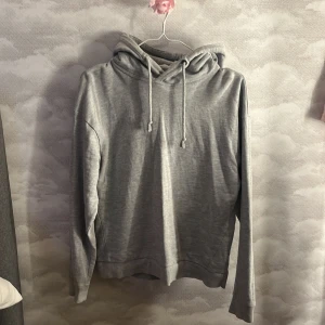Grå hoodie från Lager 157 med huva - En stilren grå hoodie från Lager 157 i storlek S. Tröjan har huva med snörning och långa ärmar, perfekt för chill dagar. Materialet är mjukt och känns skönt mot huden. Enkel design utan mönster eller tryck, passar dig som gillar basic och comfy.