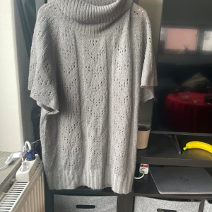 Grå stickad polotröja Soul River XL - Säljer en grå stickad polotröja från Soul River i storlek XL. Tröjan har ett snyggt hålmönster, bred polokrage och korta ärmar. Perfekt för dig som gillar oversized och mysiga vibes. Ribbad kant nedtill och vid kragen för extra stilpoäng.