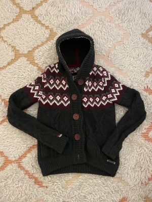 Mörkgrå stickad hoodie från Superdry - Riktigt snygg och varm stickad hoodie/cardigan ifrån superdry. Storlek S men passar XS, ca 160-175cm. Hör av dig vid minsta fundering 