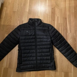 Svart pufferjacka från Puma - Svart träningsjacka från Puma i storlek M.  Grymt material och perfekt för kyliga träningar då den är lättvikt och varm. Kan användas både under och efter träning. Nypris 1000kr