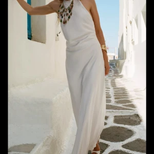 Medellång satinklänning med öppen rygg - Supersnygg vit långklänning från Zara med tunna axelband som korsas i ryggen och öppen rygg. Klänningen har en slät, glansig yta och faller mjukt längs kroppen. Perfekt för sommarens alla tillfällen, med en elegant och minimalistisk look. Dessutom är den perfekt nu inför nyår! 💗