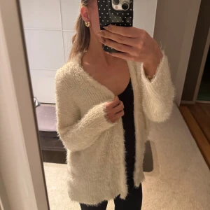 Fluffig vit kofta i stickad material - Säljer en supermjuk och fluffig vit kofta med lång ärm och öppen front. Koftan är stickad och har en avslappnad passform som är perfekt för att mysa i under kyliga dagar. Passar dig som gillar en enkel men cozy stil.🩷
