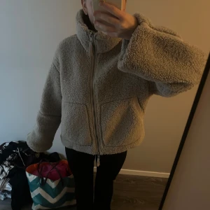 Beige teddyjacka med dragkedja - Mysig beige teddyjacka med hög krage och breda ärmar. Säljer då den inte längre kommer till användning! Kommer från h&m