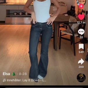 Low waist bootcut mörkblå jeans - Säljer ett par mörkblå bootcut jeans med vita kontrastsömmar och klassisk femficksdesign. Jeansen har låg midja och är tillverkade i jeansmaterial med en snygg passform som sitter tajt upptill och släpper ut vid benen. Perfekta för dig som gillar retrovibbar och markerade detaljer. Nya utan prislapp