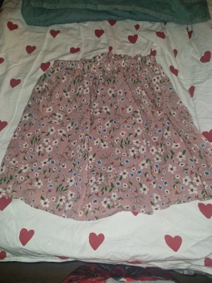 Blommig rosa kortkjol från Shein Teen - Söt rosa kortkjol från Shein Teen med blommigt mönster i vitt, blått och grönt. Kjolen har en elastisk midja och är gjord i ett lätt syntetmaterial som känns skönt mot huden. Perfekt för dig som gillar färgglada och romantiska plagg.