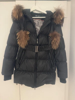 Holliesjacka - Varm äkta dunjacka från Hollies med midjebälte och avtagbara detaljer i äkta päls. Använd vid tre tillfällen, inga defekter 💕Storlek 40 men lite liten  i storlek så skulle säga 38/M. 💕Köpt för ca 8 år sedan och kostade då runt 4000kr. 🌸