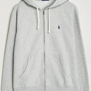 Grå hoodie från Polo Ralph Lauren - Snygg grå hoodie från Polo Ralph Lauren med klassisk blå logga på bröstet. Tröjan har huva med vita snören, hel dragkedja och två stora fickor framtill. Perfekt för chill dagar och streetwear-stil. Mjuk bomullsmix som är skön att bära.