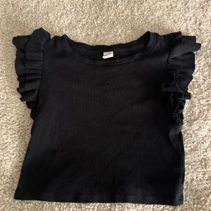 Svart ribbad topp med volangärmar - Säljer denna jättefina topp då den inte andvänds och är för kort. Pris kan diskuteras💕