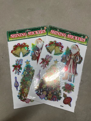 Shining Stickers 3 för 2 - Två ark med glittriga julklistermärken – tomtar, julgranar, klockor och pynt. Perfekt för att dekorera anteckningsböcker, mobilskal eller julklappar! Lätta att använda, återanvändbara och ger extra festlig känsla till dina saker.