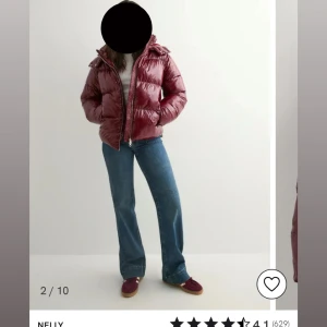 Vinröd pufferjacka från Nelly - Säljer en glansig vinröd pufferjacka från Nelly med huva och dragkedja framtill. Se defekt på bild 4