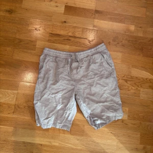 Beige linneshorts från Dressmann - Snygga beige shorts från Dressmann i linnemix med elastisk midja och snörning. De har två sidofickor och en bakficka med knapp. Perfekta för varma dagar och ger en avslappnad men stilren vibe.