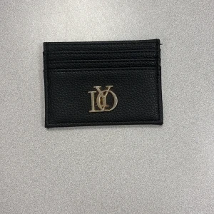 svart plånbok med guldigt märke - Stilrent svart plånbok i präglat skinn med guldfärgad logga framtill. Fodralet har flera kortfack och en ljus insida. Perfekt för dig som vill ha koll på korten med en snygg accessoar pris kan diskuteras