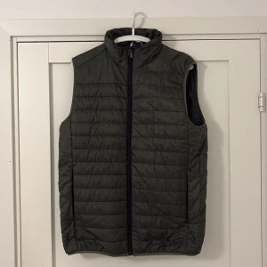Mörkgrön väst - Snygg mörkgrön dunväst med quiltad design och hög krage.  Använd ett fåtal gånger. Storlek M