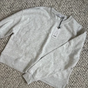 Ljusgrå sweatshirt från 157 - En stilren ljusgrå sweatshirt från 157 med rund halsringning och ribbade muddar. Tröjan är i mjuk bomullsmix och har en klassisk, avslappnad passform. Perfekt att slänga på sig till jeans eller mjukisbyxor.