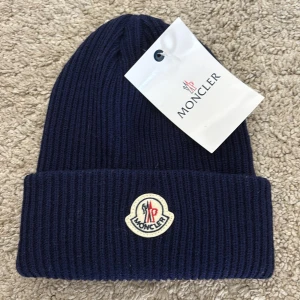 Mössa - Snygg mörkblå ribbstickad mössa med klassisk logotyp framtill. Mössan är tillverkad i mjuk ull och har en uppvikt kant för extra stilpoäng. Perfekt accessoar för kyliga dagar och en självklar detalj till vinterlooken.