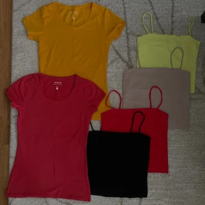 Färgglada toppar och linnen  - Säljer ett paket med två t-shirts i rött och gult samt fyra linnen i svart, rött, beige och ljusgul. T-shirtsen har rund hals och kort ärm, linnena är ärmlösa med smala axelband. Alla i mjuk bomull, perfekta för sommaren och att mixa och matcha. xs-s
