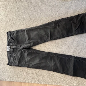 Svarta jeans från Jacob Cohen - Säljer ett par svarta jeans från Jacob Cohen med klassisk femficksdesign och snygga detaljer som broderad logga på myntfickan och metallknapp med J. Jeansen har raka ben och är tillverkade i mjukt bomullstyg med en skön passform.