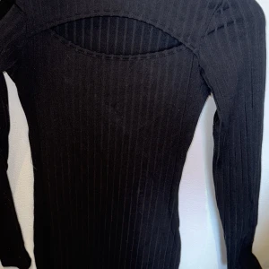 Svart ribbad långärmad klänning - Säljer en svart långärmad klänning med ribbad struktur. Klänningen har en slim passform och är tillverkad i ett stretchigt material som sitter snyggt på kroppen. Perfekt för dig som gillar stilrena och trendiga plagg.