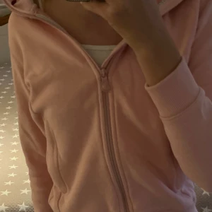 Ziphoodie från Pelle P - Ljusrosa zip hoodie från Pelle P med dragkedja hela vägen, huva med grått foder och ribbade muddar. Jackan har två fickor framtill och en svart rund logotyp på ärmen. Inte använd mycket, så i bra skick. Nypris:899 kr. Den är i stl 150, men är bara lite liten för mig som är 170 cm lång (så skulle säga kanske XS) så passar någon som är lite kortare, hör av er om frågor!❤️