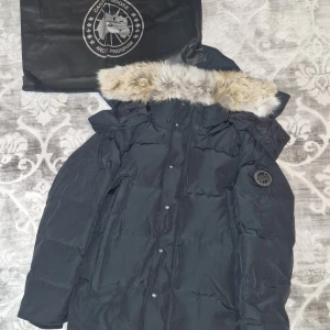 ❄️Canada Goose Wyndham❄️ - Canada goose Wyndham🌟. Svart färg med svart logga, väldigt klassiskt och fin. Håller dig varm under vintern. Storlek M. Kommer med original påse från Canada Goose. Har du några fler frågor så skicka ett dm☺️