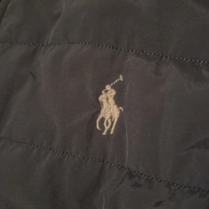 Ralph Lauren jacka - Jacka från Polo Ralph Lauren med broderad logga på bröstet. Jackan har dragkedja framtill, snedställda fickor med tryckknappar och en ärmficka med dragkedja. ÄKTA! 