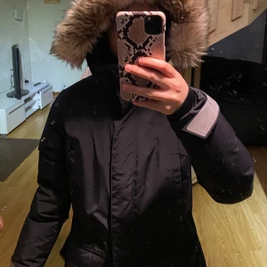 Svart dunjacka med fuskpäls - Säljer en svart dunjacka med stor huva och fluffig fuskpäls i beige ton. Jackan har långa ärmar och dragkedja. Perfekt för vintern! Använd en vinter säsong. Storlek S/36 men passar även xs. Pris kan diskuteras😊
