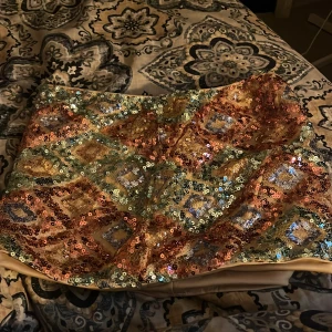 Paljettprydd kortkjol i guld och blått - Säljer en superglittrig kortkjol täckt av paljetter i guld, blått, grönt och koppar. Kjolen har ett färgstarkt mönster med geometriska former och är perfekt för dig som vill sticka ut. Den har en figurnära passform och är fodrad för extra komfort.