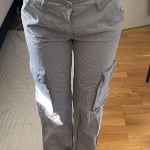 Grå cargopants från Perfect Jeans - Snygga grå cargopants från Perfect Jeans med raka ben och flera stora fickor på sidorna och bak. Byxorna har normal passform, bälteshällor och stängs med knapp och dragkedja. 