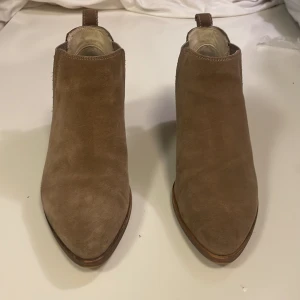 Beige mocka chelsea boots Vagabond - Snygga beige chelsea boots från Vagabond i mjuk mocka. Skorna har spetsig tå, låg klack och elastiska partier på sidorna för enkel påtagning. Perfekta för dig som gillar stilrena och trendiga boots med en klassisk touch.