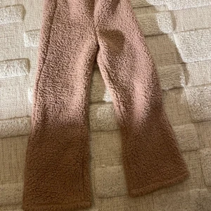 Rosa/beige fleecebyxor från Lindex, fluffiga.  - Rosa/beige, fluffiga byxor. Väldigt mjuka och varma. Storlek 134/140. Använda ett fåtal gånger. 👌står ”stay cool” i resåren längs upp. 