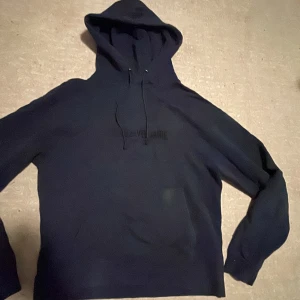 Mörkblå hoodie från Zadig & Voltaire - Säljer en mörkblå hoodie från Zadig & Voltaire med tryck framtill och coola snören i huvan. Tröjan har klassisk känguruficka och långa ärmar. Perfekt för dig som gillar streetstyle och vill ha något bekvämt och snyggt.