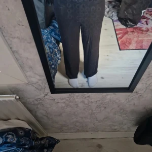 Svarta byxor från Kappahl, stl 146 - Svarta byxor från Kappahl i storlek 146. De har ett rakt och avslappnat snitt med midja som sitter bekvämt. Materialet är mjukt och stretchigt, perfekt för chill dagar. Diskret cirkelmönster upptill ger en cool touch. Passar dig som gillar enkel och stilren look.