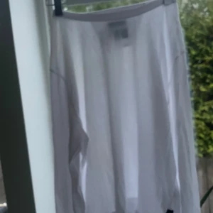 Vit långkjol från Tiger of Sweden Jeans - Säljer en vit tröja från Tiger of Sweden Jeans i storlek Large.  Enkel och stilren med rak passform och tillverkad i ett lätt bomullsmaterial. Perfekt för dig som gillar minimalistisk och clean stil.