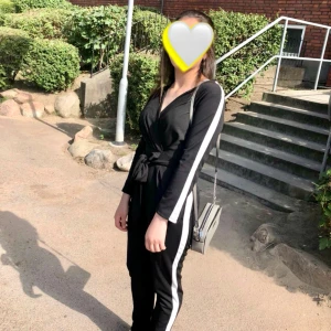 Svart jumpsuit med vita ränder - Snygg svart jumpsuit med långa ärmar och vita ränder längs sidorna. 