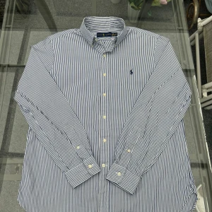 Ralph Lauren blåvit randig skjorta (strl 40/41 M/L) - Snygg och klassisk skjorta från Ralph Lauren i blåvita ränder. Har button-down-krage, broderad polo-logga och är tillverkad i 100 % bomull – riktigt skön kvalitet!  Storlek: 16 / 40–41 (motsvarar M/L), halsmått ca 40–41 cm. Normal passform. Skjortan är i mycket fint skick, inga fläckar eller slitage.  Perfekt till både vardag, kontor eller mer uppklädda tillfällen – funkar lika bra instoppad i chinos som öppen över en t-shirt för en mer avslappnad look.  📦 Snabb leverans 💎 Från rök- och djurfrit