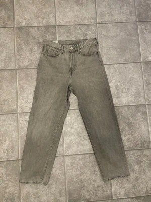 Grå loose fit jeans från H&M - Säljer ett par grå jeans från H&M i loose fit-modell. De har klassisk femficksdesign, raka ben och normal midja. Jeansen är tillverkade i bomull och har en snygg, lite tvättad grå ton som ger en chill vibe.